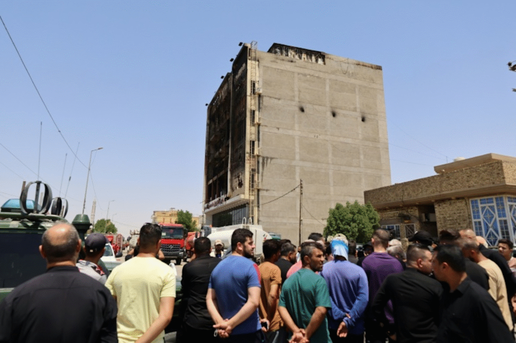 Civiles iraquíes observan las devastadoras secuelas del incendio en el hipermercado Corniche, en Al-Kut, Irak