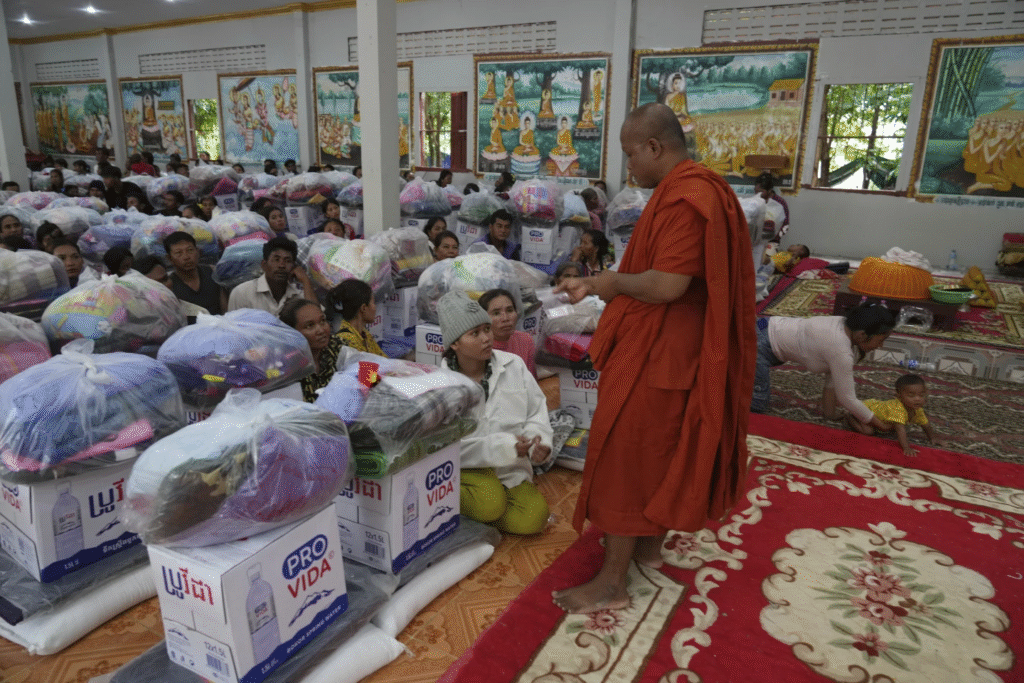 Un monje budista camboyano saluda a los aldeanos que esperan recibir provisiones donadas por una organización benéfica para refugiados, en el distrito de Srey Snam, provincia de Siem Reap, Camboya, el lunes 28 de julio de 2025, en medio de los combates entre Tailandia y Camboya. (Foto AP)