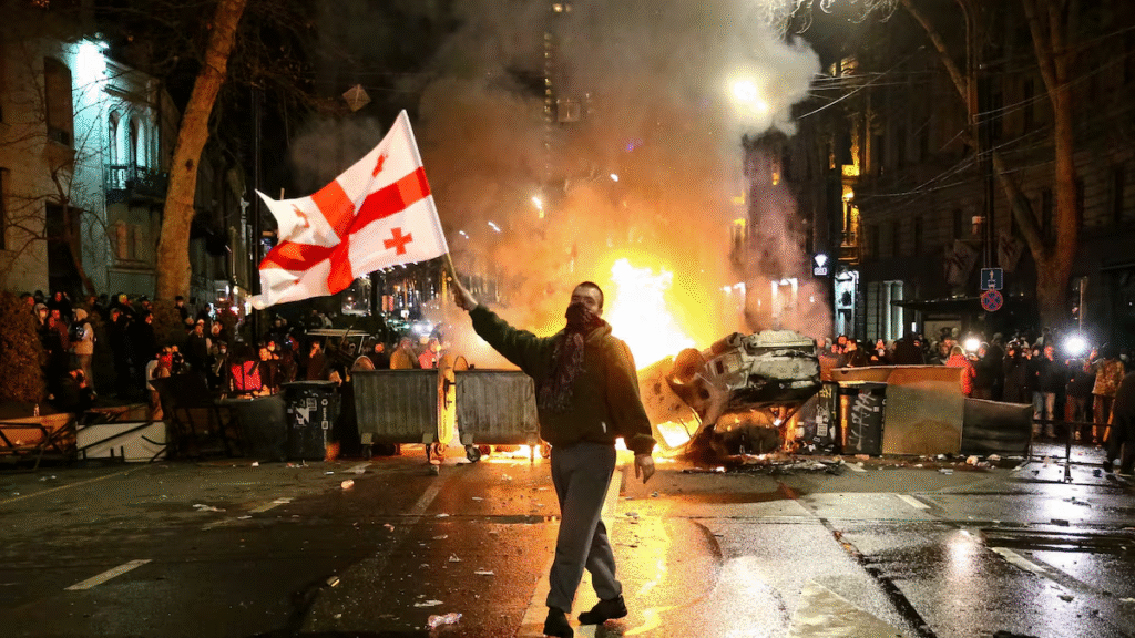 Un hombre alza la bandera de Georgia ante una barricada en llamas frente al Parlamento, la noche del 8 al 9 de marzo.
Foto: ZURAB TSERTSVADZE (AP) | Vídeo: Reuters