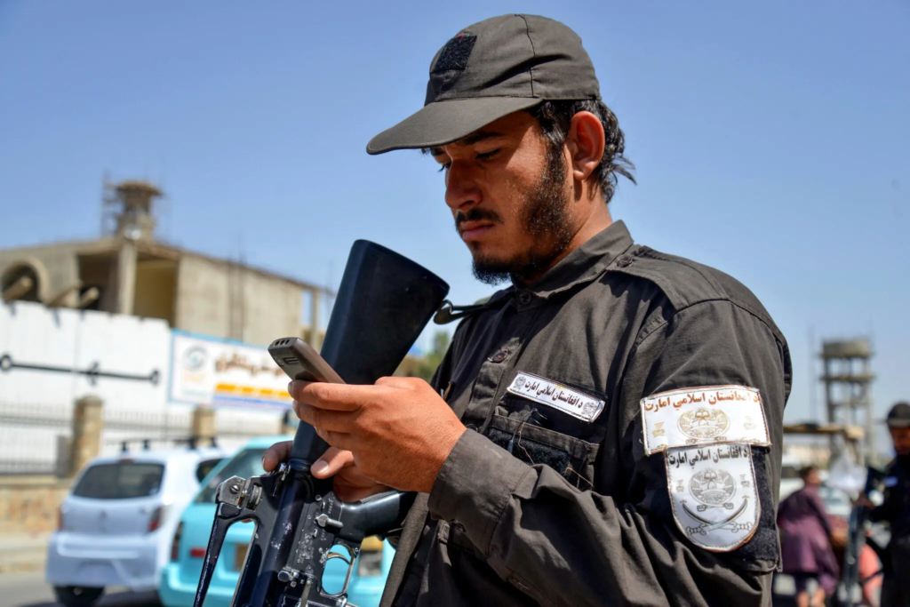 Un agente de seguridad talibán usando un teléfono móvil en Kandahar, Afganistán, 2025